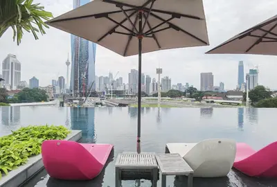 a table and chairs with an umbrella in front of a body of water at MyCrib Opus Recidence 3 bedroom BBintang in Kuala Lumpur