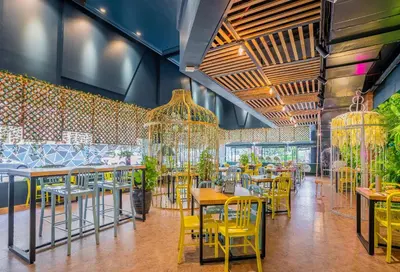a restaurant with yellow chairs and tables and chandeliers at Hotel Olympic Malaysia Kuala Lumpur in Kuala Lumpur