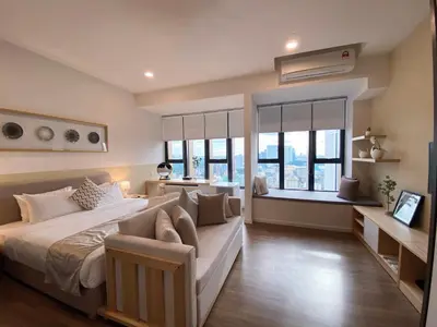 a bedroom with a large bed and a couch and windows at Ceylonz Lifestyle Suites @ Bukit Bintang in Kuala Lumpur