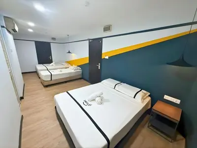 a room with two beds and a chair in it at Smile Hotel Chow Kit PWTC in Kuala Lumpur