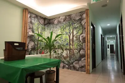 a wall mural in a hallway with a green table at Rain Forest Hotel in Kuala Lumpur