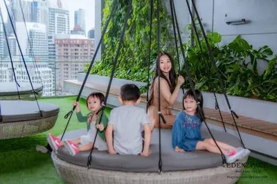 a woman and three children sitting on a swing at Ceylonz Suites by EdenZpace in Kuala Lumpur