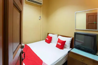 a small bedroom with a bed with red pillows and a tv at SPOT ON 90137 Casavilla Hotel Pudu in Kuala Lumpur