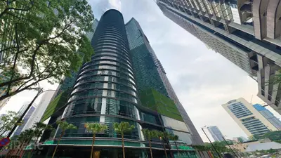 a tall glass building with trees in front of it at Sky Suites KLCC by iRent365 in Kuala Lumpur