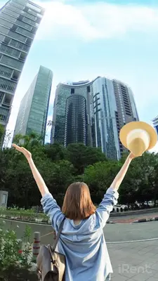 a woman with her arms up in front of a city at Sky Suites KLCC by iRent365 in Kuala Lumpur