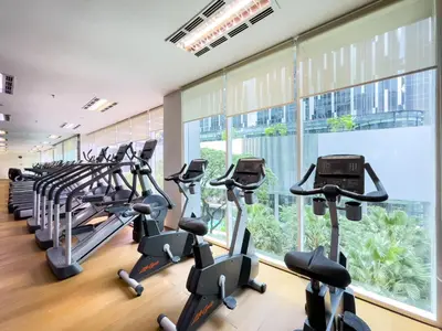 a gym with treadmills and ellipticals in front of a large window at Soho Suites KLCC by Rest Kuala Lumpur in Kuala Lumpur