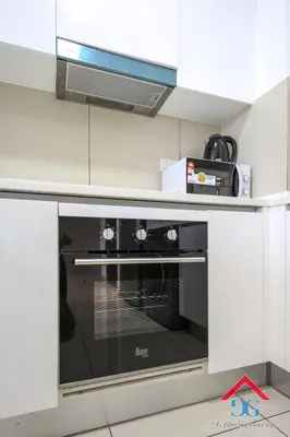 a black oven in a kitchen with white cabinets at Astoria Ampang By Grabstay in Kuala Lumpur