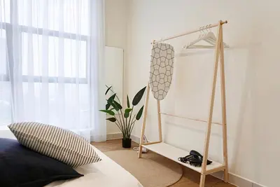 a bedroom with a bed and a clothes rack at Arte Mont Kiara by CozyNest in Kuala Lumpur