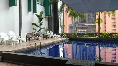a swimming pool with chairs and tables and a building at One Maxim Residence at Taragon in Kuala Lumpur