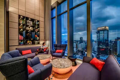 a woman sitting in a room with a view of a city at Capri by Fraser, Bukit Bintang in Kuala Lumpur