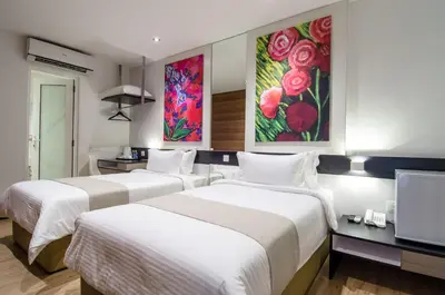 two beds in a hotel room with paintings on the walls at 12FLY Hotel Kuala Lumpur in Kuala Lumpur