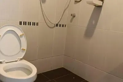 a bathroom with a toilet with a hose on the wall at Mars Hotel in Kuala Lumpur