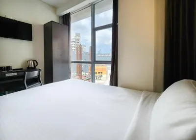 a bedroom with a large white bed and a window at Izumi Hotel Bukit Bintang Kuala Lumpur in Kuala Lumpur