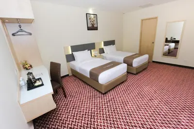 a hotel room with two beds and a mirror at Metro Hotel Bukit Bintang in Kuala Lumpur