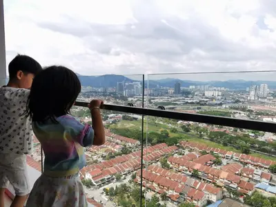 a couple of children standing on a balcony looking at the city at Aishiteru Homestay in Kuala Lumpur