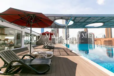 a swimming pool with chairs and an umbrella on a building at D'Majestic Premier Suites Kuala Lumpur in Kuala Lumpur
