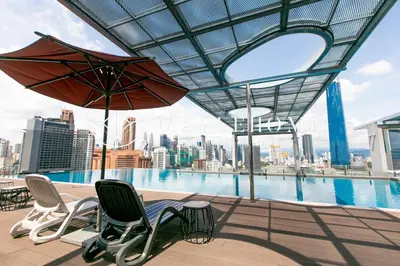 a patio with chairs and an umbrella and a pool at D'Majestic Premier Suites Kuala Lumpur in Kuala Lumpur