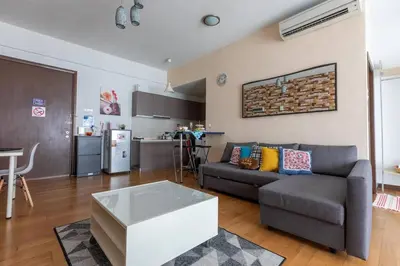 a living room with a couch and a kitchen at Cozy Regalia KL 吉隆玻 LRT & KTM @1 Parking & WIFI in Kuala Lumpur