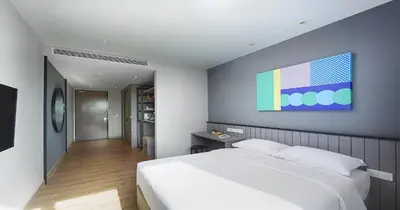 a bedroom with a white bed and a painting on the wall at Hotel Komune Living & Wellness Kuala Lumpur in Kuala Lumpur