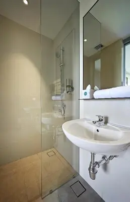 a bathroom with a sink and a glass shower at Hotel Komune Living & Wellness Kuala Lumpur in Kuala Lumpur