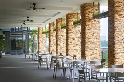 a dining area with tables and chairs in a building at Hotel Komune Living & Wellness Kuala Lumpur in Kuala Lumpur