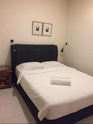 a white bed with a black headboard and two towels on it at FKI INTERNATIONAL HOTEL in Kuala Lumpur