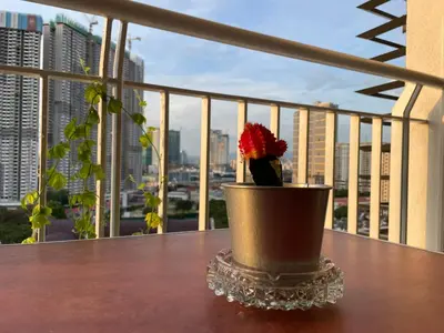 a flower in a pot on a table on a balcony at Private Jacuzzi Staycation at KL City 1014 in Kuala Lumpur