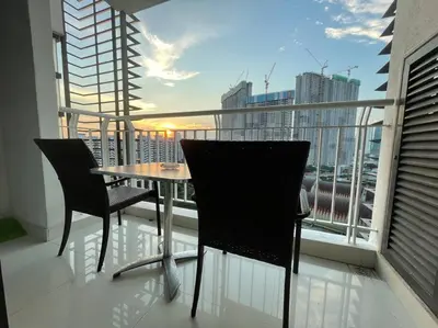 a table and chairs on a balcony with a view of a city at Private Jacuzzi Staycation at KL City 1014 in Kuala Lumpur