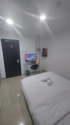 a bedroom with a large white bed and a television at ONE AMPANG HOTEL in Ampang