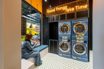 a woman sitting in front of three washing machines at lyf Chinatown Kuala Lumpur in Kuala Lumpur