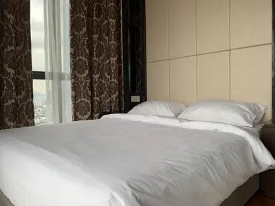 a bed with white sheets and pillows in front of a window at Nana's at Dorsett Residence Bukit Bintang in Kuala Lumpur
