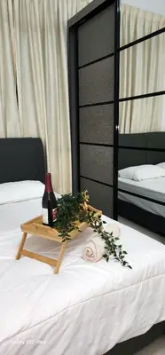 a table with a bottle of wine on a bed at Legasi Kampung Baru apartment by rumahrehat in Kuala Lumpur
