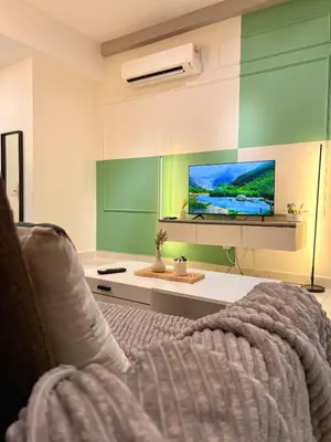 a living room with a couch and a tv at Modern Suites at Arte Mont Kiara BY Iconique in Kuala Lumpur