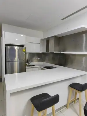 a kitchen with a white counter and two stools at M City 2 DUPLEX BEDROOM KLCC in Kuala Lumpur