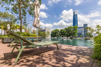 a green bench with an umbrella and a table with water at Continew Residensi by Airhost in Kuala Lumpur