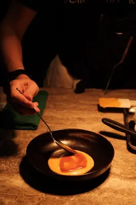 a person holding a spoon with an egg in a frying pan at Else Kuala Lumpur, a member of Design Hotels in Kuala Lumpur