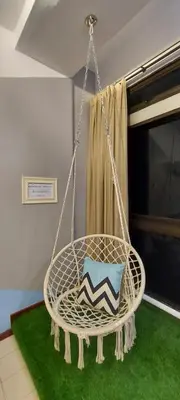 a hanging chair with a pillow on a green rug at Fahrenheit 88, Kuala Lumpur 11 in Kuala Lumpur