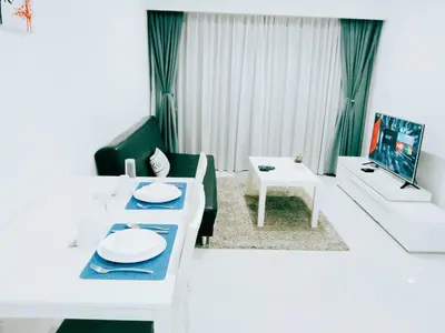 a white living room with a table and a couch at Mercu Summer Suites KLCC by Star Residence in Kuala Lumpur