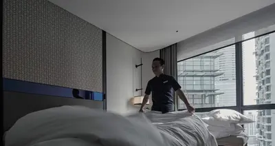 a man standing on top of a bed in a room at Amari Kuala Lumpur in Kuala Lumpur
