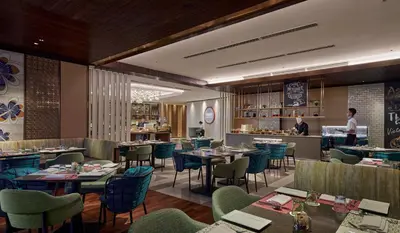 a restaurant with tables and chairs and a person in the background at Amari Kuala Lumpur in Kuala Lumpur