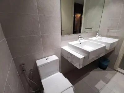 a bathroom with two sinks and a toilet and a mirror at The Ooak Suites and Residence@ Kiara 163 in Kuala Lumpur