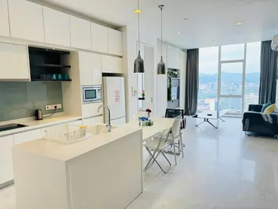 a kitchen with white cabinets and a living room at The Face Platinum Suites KLCC in Kuala Lumpur