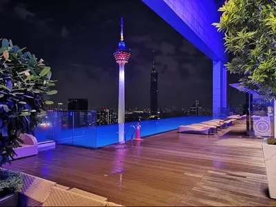 a rooftop deck with a view of the space needle at night at The Face Platinum Suites KLCC in Kuala Lumpur