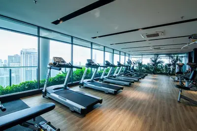 a gym with a row of treadmills and windows at Colony @ Kampung Baru by Plush in Kuala Lumpur