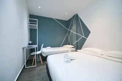 a bedroom with two beds and a blue wall at Meta Hotel in Kuala Lumpur