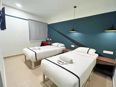 a room with two beds and a blue wall at Smile Hotel Titiwangsa Pekeliling Sentul in Kuala Lumpur