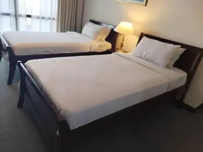 two beds in a hotel room next to a lamp at KL BERJAYA TIMES SQUARE SERVICe APARTMENT in Kuala Lumpur