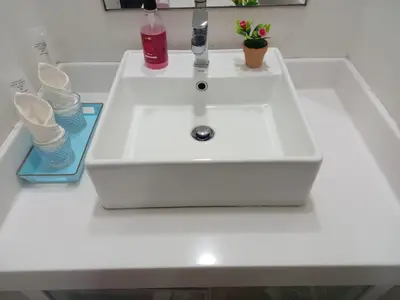 a white sink with two glasses and a bottle on a counter at Summer Suites Klcc by Malenehom in Kuala Lumpur