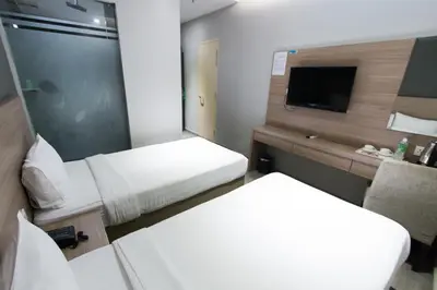 a small hotel room with two beds and a tv at Hotel 99 Kuala Lumpur City in Kuala Lumpur