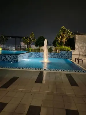 a fountain in the middle of a pool at night at Homestay D'Zara in Kuala Lumpur